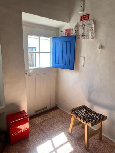 a room with a table and a blue door and a window at Casa na aldeia in Albernoa