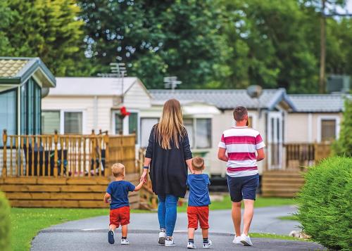 a woman and two boys walking down a driveway at Woodland Vale Holiday Park in Ludchurch
