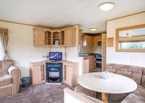 a caravan living room with a table and a kitchen at Woodland Vale Holiday Park in Ludchurch