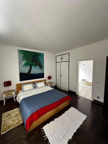 a bedroom with a bed with a tree painting on the wall at Casa do Trevo in Salir de Porto