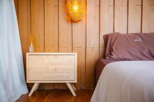 a bedroom with a bed and a nightstand with a lamp at เต็นท์ดูดาว1 แอร์ ม่อนแจ่ม วิวดอยหลวงเชียงดาว in Mon Jam