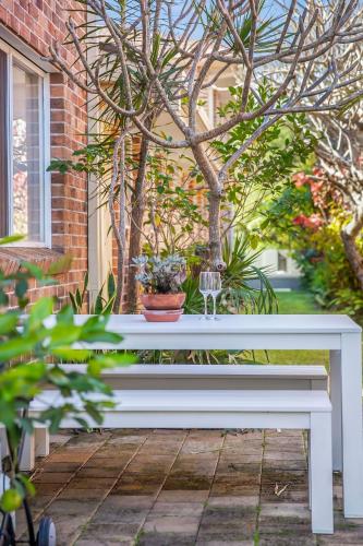 a white bench sitting in front of a tree at Hoppy's Place in Sawtell