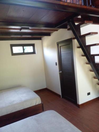 a room with two beds and a staircase with a door at Casa Santa Teresita - Cabaña Máster in El Progreso