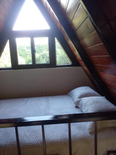 a bed in a room with windows in a attic at Casa Santa Teresita - Cabaña Máster in El Progreso