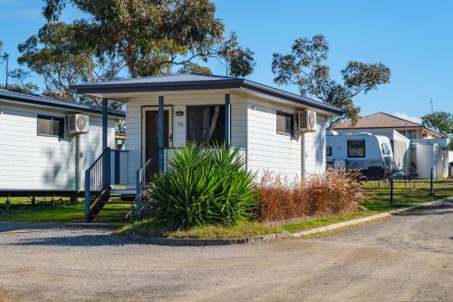 a small white house with a porch on a street at Tamworth Holiday Park in Tamworth