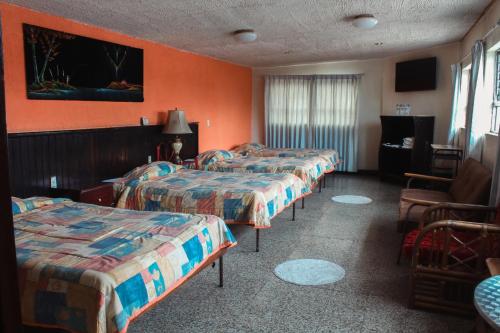 una habitación de hotel con 3 camas y una silla en El Centro Hotel, en Quetzaltenango