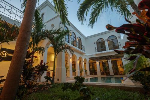 a building with palm trees in front of it at María Hotel Boutique ADULTS ONLY in Mérida