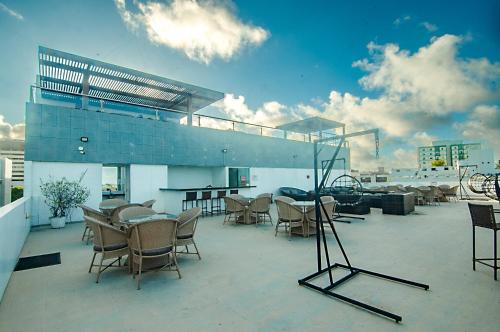 a patio with chairs and tables on a roof at Flat de frente à praia in João Pessoa