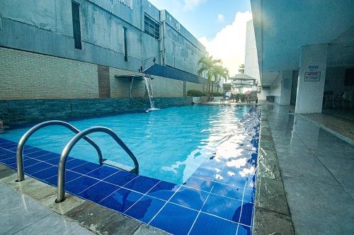 a swimming pool with blue tiles in a building at Flat de frente à praia in João Pessoa