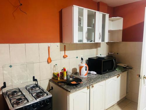 eine kleine Küche mit Herd und Mikrowelle in der Unterkunft Hermoso Depto in La Playa Bejarano