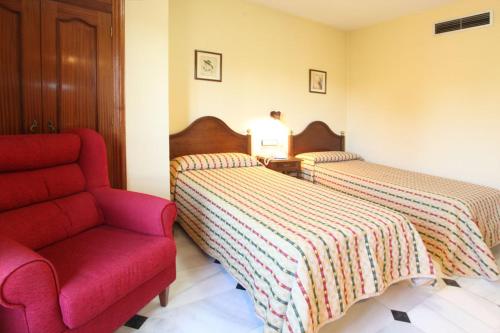 a bedroom with two beds and a red chair at El Cisne in Córdoba
