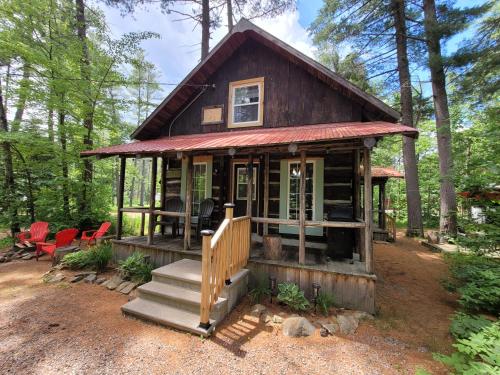 a small cabin in the woods with red chairs at Pine Ridge Park Campground in Pembroke