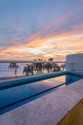a pool with a view of the ocean and palm trees at Maravilloso departamento frente al mar, Acapulco in Acapulco