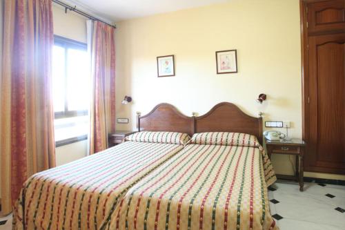 a bedroom with a bed with a striped comforter and a window at El Cisne in Córdoba