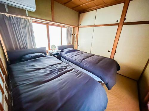 zwei Betten in einem kleinen Zimmer mit Fenster in der Unterkunft 癒しの宿 Villa ZEN 讃岐白鳥 in Higashikagawa
