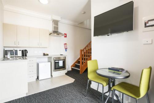 a kitchen with a table and yellow chairs in a room at Nightcap at the Ship Inn in Busselton