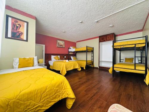 a bedroom with two beds with yellow sheets and wooden floors at Hotel Las Americas in Cuenca