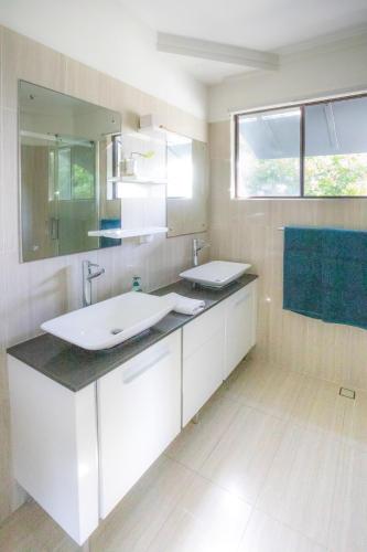 a bathroom with a white sink and a mirror at Luxe Ocean View Retreat - Acutterbove Straddie in Point Lookout
