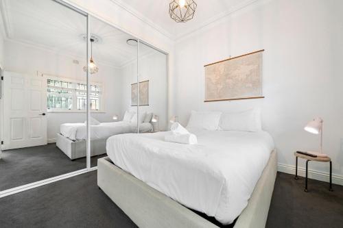 a white bedroom with two beds and a window at Charming 3BR in Top Spot in Sydney