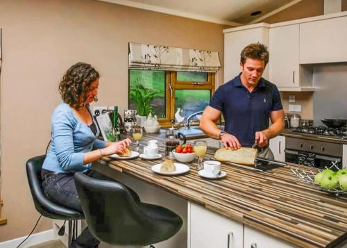 a man and a woman preparing food in a kitchen at Upton Lakes Lodges in Cullompton
