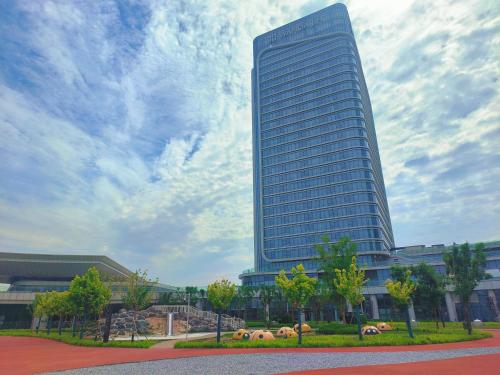 a tall building in front of a cloudy sky at Wanda Jin Xiaohe Xincheng in Taiyuan