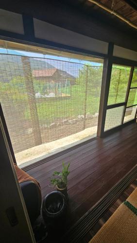 a room with a large window with a plant next to it at 民宿SAZANAMi in Hagi