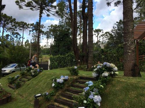 a woman sitting in a yard with flowers at Refúgio das Araucárias in Campos do Jordão