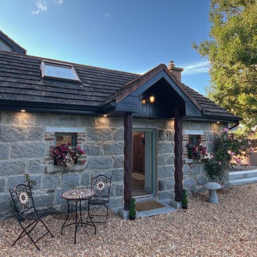 a stone cottage with a table and chairs in front of it at Holly Cottage Cozy Loft in Aghade Bridge