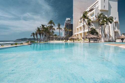 a large swimming pool in front of a building at Maravilloso departamento frente al mar, Acapulco in Acapulco