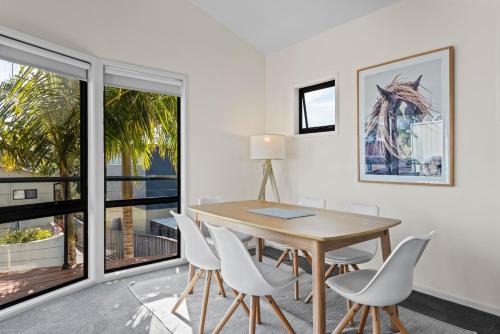 a dining room with a wooden table and white chairs at Perfect Jervis Bay location & fresh modern living in Vincentia