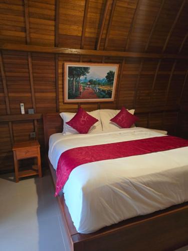 ein Schlafzimmer mit einem großen Bett mit roten Kissen in der Unterkunft Dudu Cottage Nusa Penida in Nusa Penida