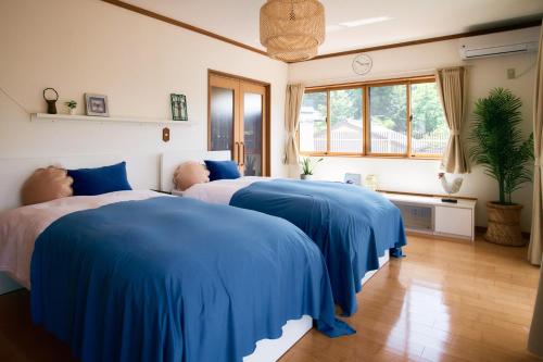 two beds in a room with blue sheets at 丘の上の貸切平屋 ペンペンハウス in Nakayama