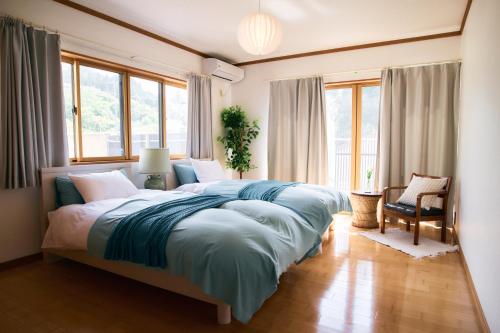 a bedroom with a large bed in a room with windows at 丘の上の貸切平屋 ペンペンハウス in Nakayama