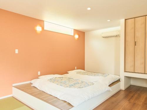 two beds in a room with orange walls at ちょこっとヴィラMaestro in Tusi