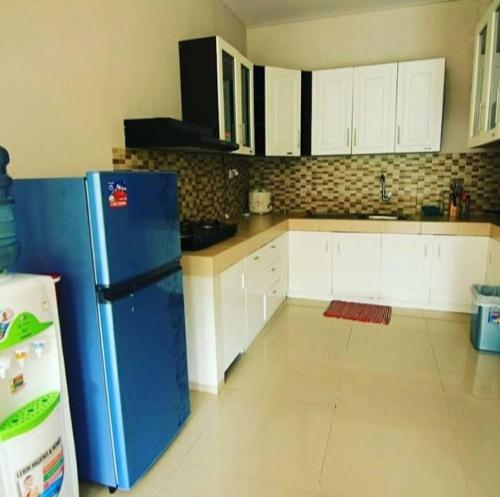 a kitchen with a blue refrigerator and white cabinets at Foursya Villa Samarinda in Loa Bakong