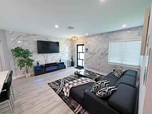 a living room with a couch and a flat screen tv at The LuxeLanding MIA- Swimming pool, Oasis Lounge, Mini Golf, BBQ and Hibachi Grill , and Outdoor Games in Miami