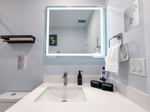 a white bathroom with a sink and a mirror at The LuxeLanding MIA- Swimming pool, Oasis Lounge, Mini Golf, BBQ and Hibachi Grill , and Outdoor Games in Miami