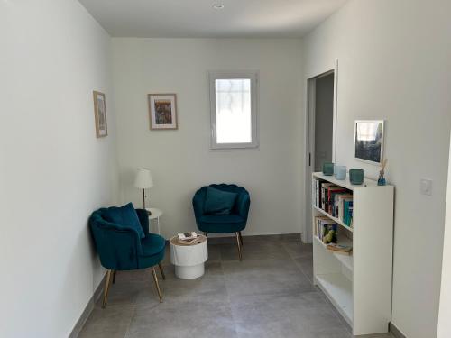 a room with two blue chairs and a book shelf at Magnifique villa avec jacuzzi in Montferrier-sur-Lez