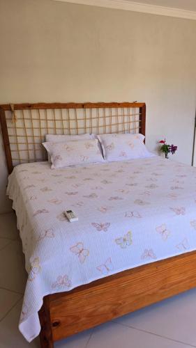 a bed with a wooden frame with a white comforter at Casa Clorophila, suíte master completa com banheira, para 3 hóspedes in Vila Velha