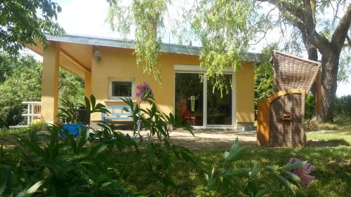 ein gelbes Haus mit einem Baum und einem Stuhl in der Unterkunft Uckermark Ferienhaus in Kuhz