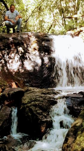 a man sitting on a rock next to a waterfall at Los Lapachos. La naturaleza es acá 