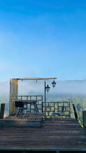 a wooden deck with a picnic table and chairs on it at Săn Mây Homestay and Coffee Măng Đen in Kon Tum
