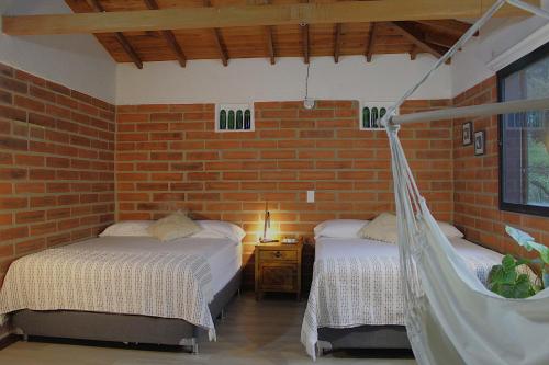 a bedroom with two beds and a brick wall at Finca Hotel Recinto de la Gruta in Copacabana