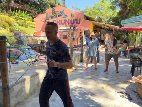 a man standing on a sidewalk holding a plate at MINCA Chunuu - glamping - coworking MINCA in Minca