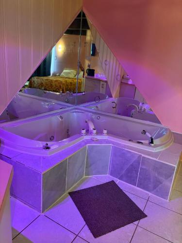 a large bath tub in a room with purple lighting at Motel Le Voyageur in Saint-Jérôme