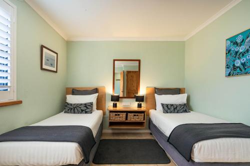 two beds in a room with a mirror at Albany Harbourside Apartments And Houses in Albany