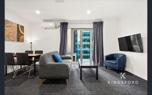 a living room with a couch chair and a table at Comfort Apartments Melbourne Central in Melbourne