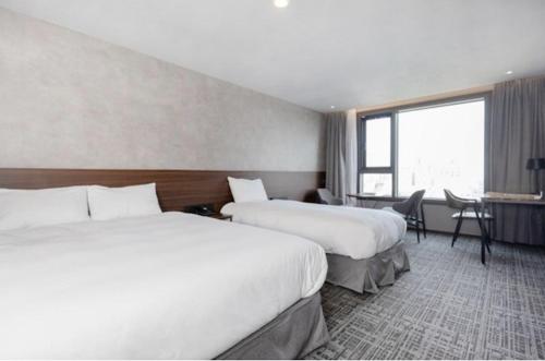 a hotel room with two beds and a window at With Stay Jeju Hotel in Jeju