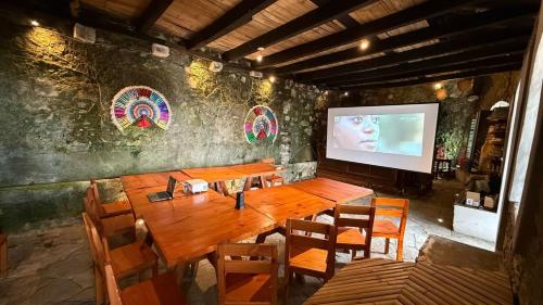 a dining room with a large wooden table and a screen at La Peña Hotel Boutique & SPA in Cuetzalán del Progreso