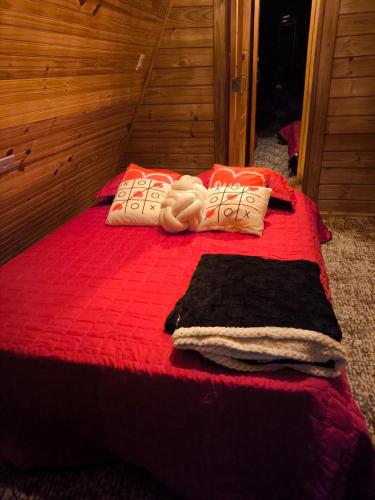 a red bed with a red blanket and towels on it at Chalé Bela Vista in Munhoz